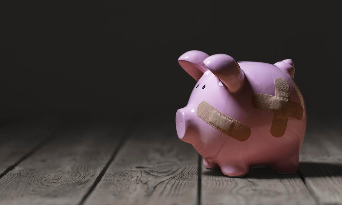 A piggy bank covered in sticking plasters