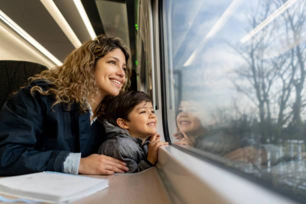 Image of a woman and a child staring out of a train window will the countryside wizzes by. Great British Rail Sale - discounted rail tickets