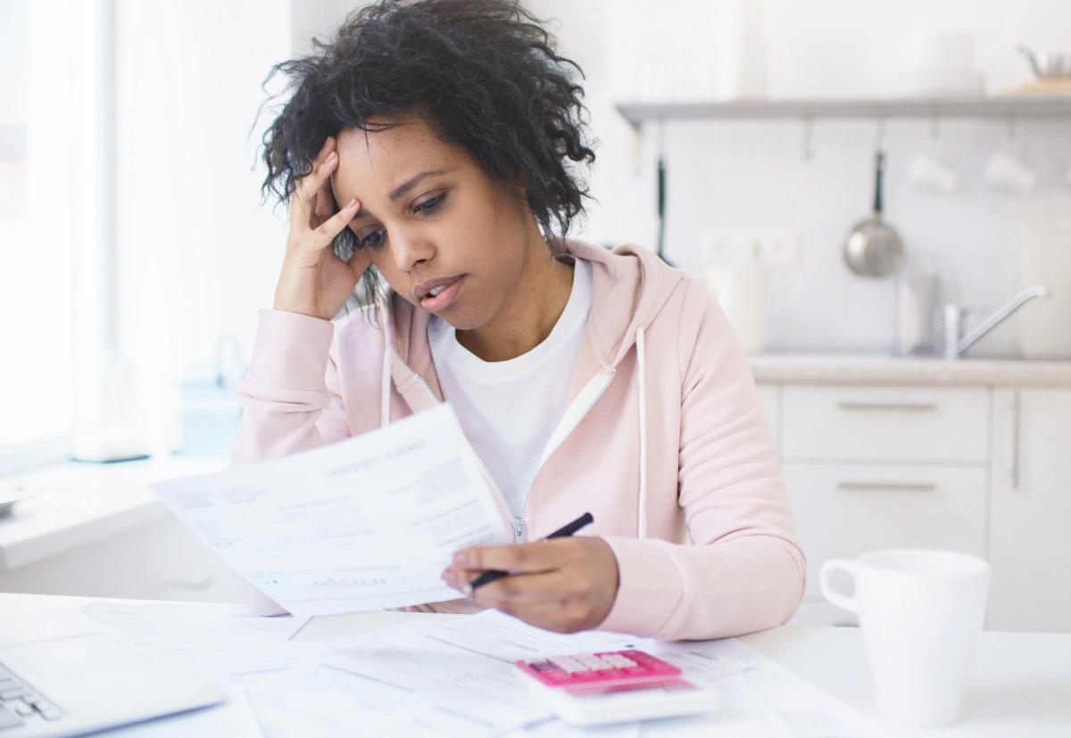 A worried woman sits at the kitchen  table and goes through her finances.