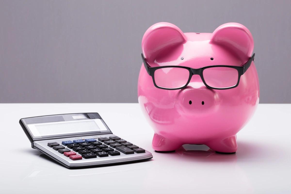 A piggy bank wearing glasses next to a calculator
