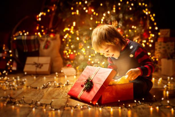 Image of a child opening a present surrounded by Christmas lights