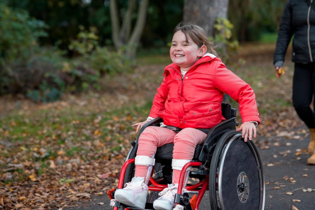 A smiling girl in a wheelchair in the park