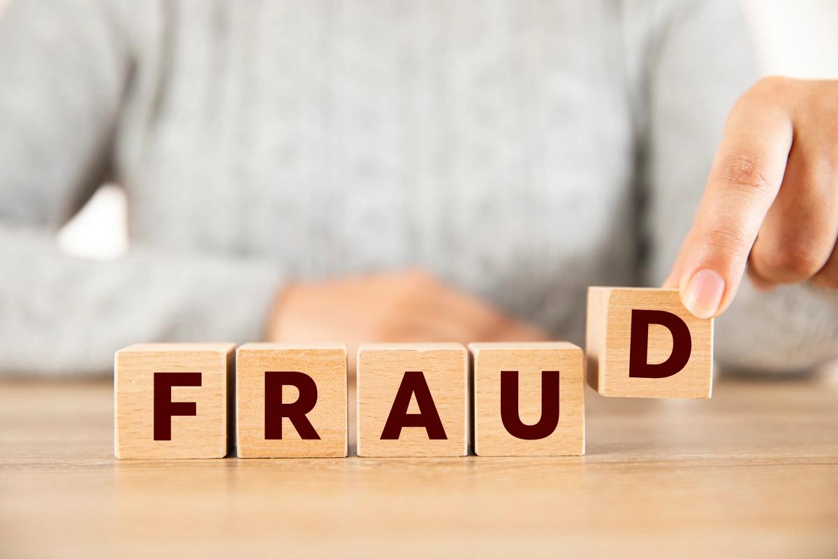 A woman spelling out fraud using wooden blocks