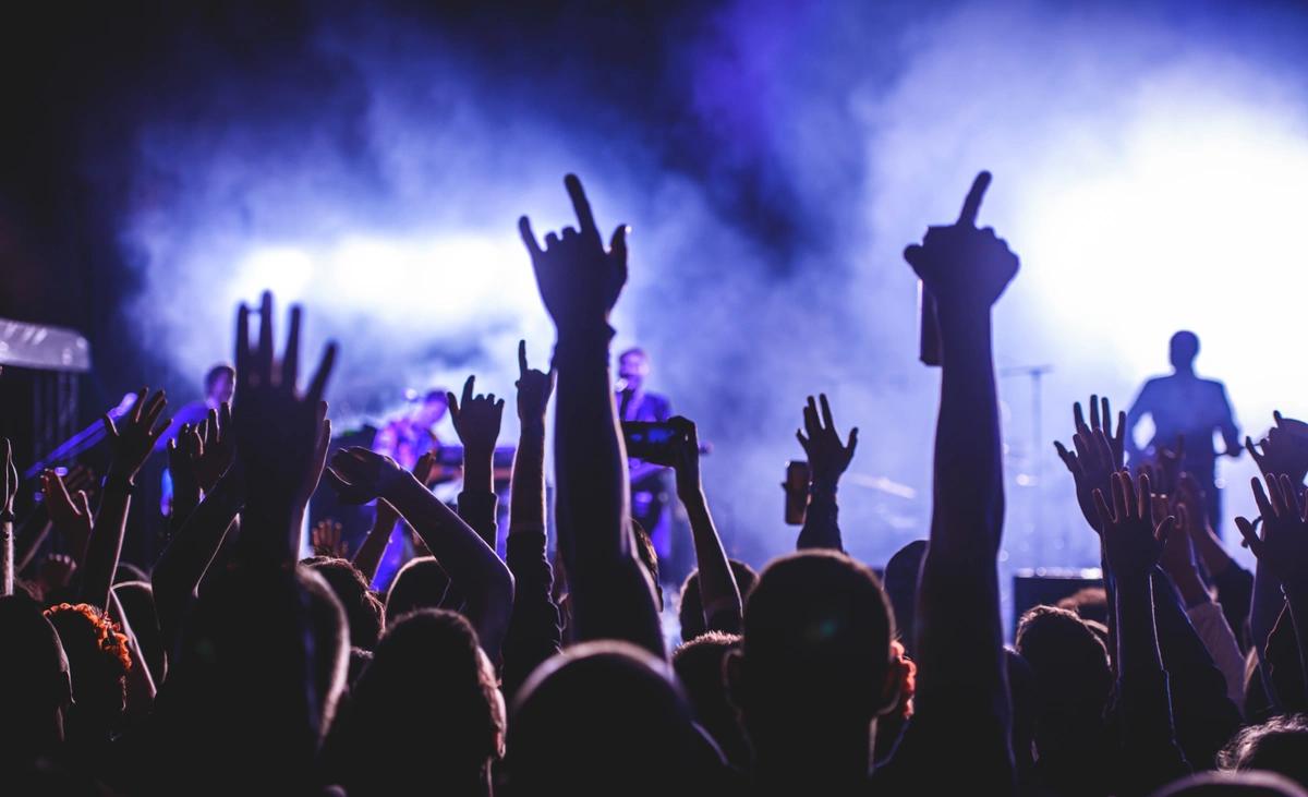 Gig goers with their hands in the air as they watch a live band
