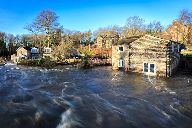 Image of a river that's flooded its bank and is up to the first storey window of a house