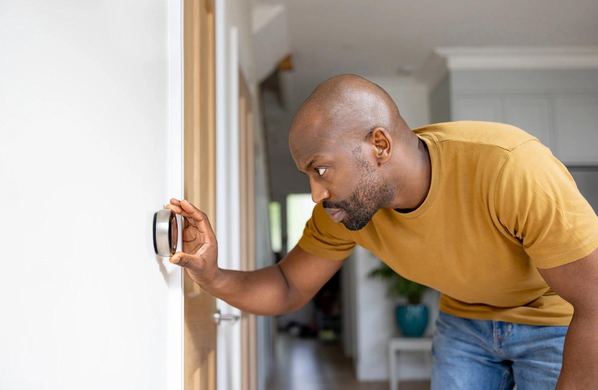 Man adjusting the temperature on the thermostat in his house
