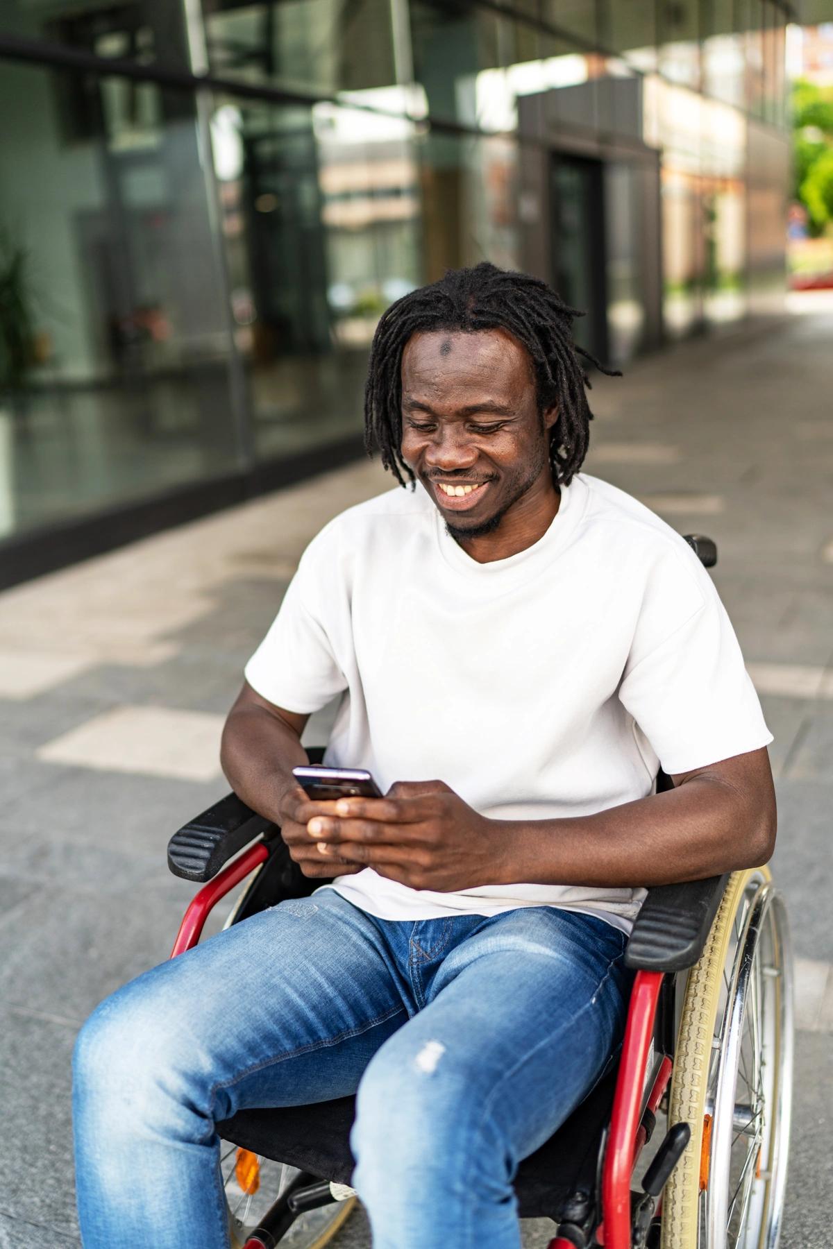Man in a wheelchair fills in an application on his phone