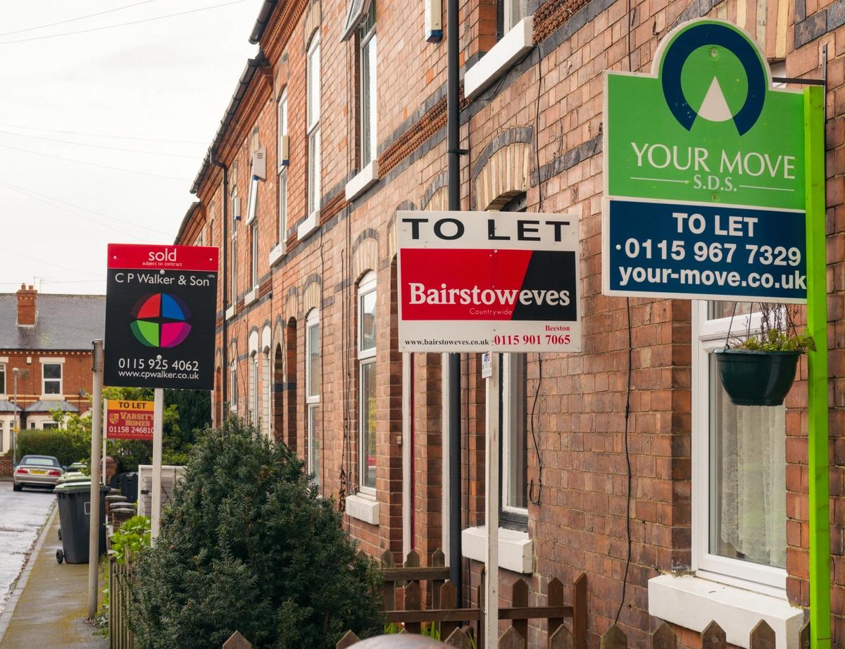 A row of terraced houses with to-let and sold signs outside