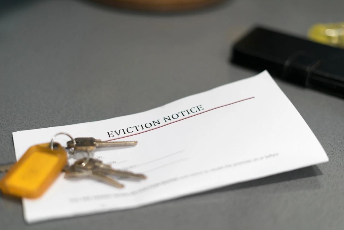 An eviction notice lying on a table with some house keys on top of it