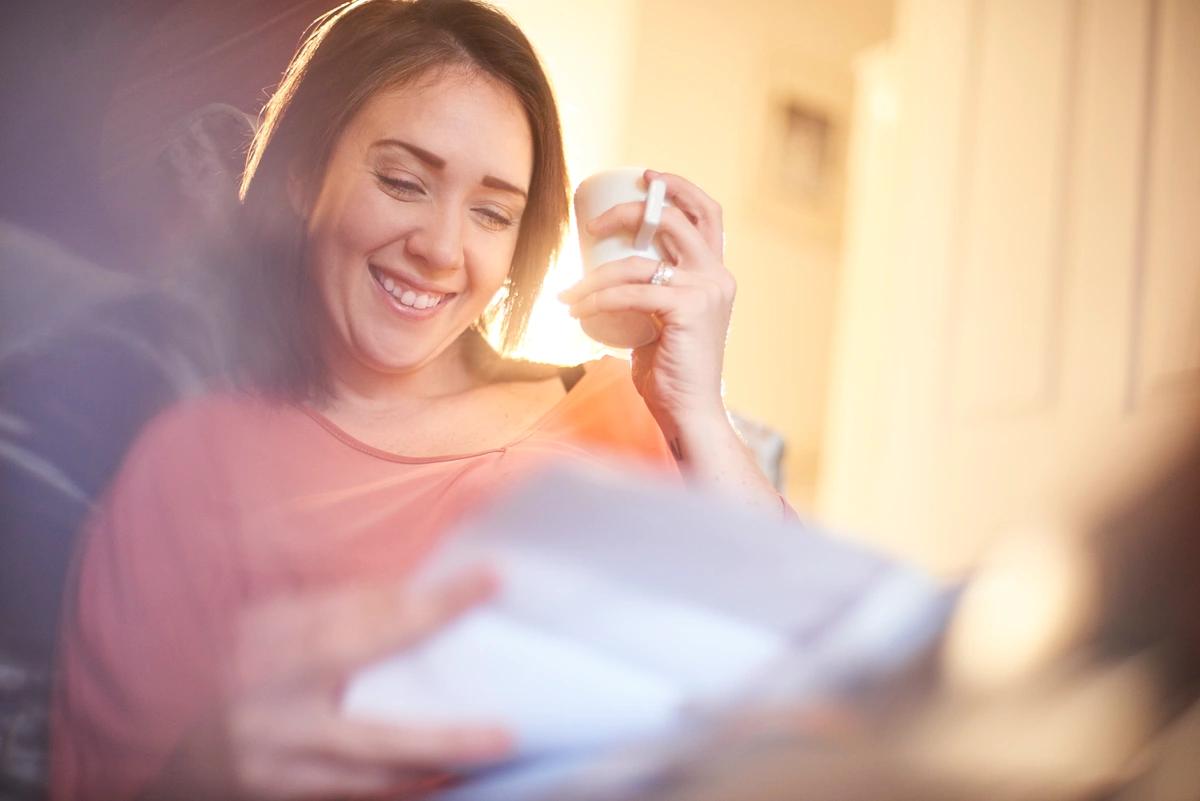 woman smiling with paperwork and coffee