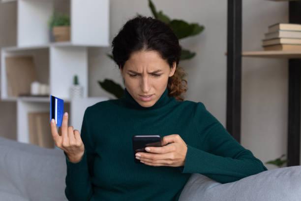 Image of women talking on the phone with her bank card in hand looking worried