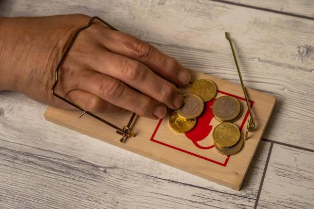 image of a hand in a mouse trap with money on one side