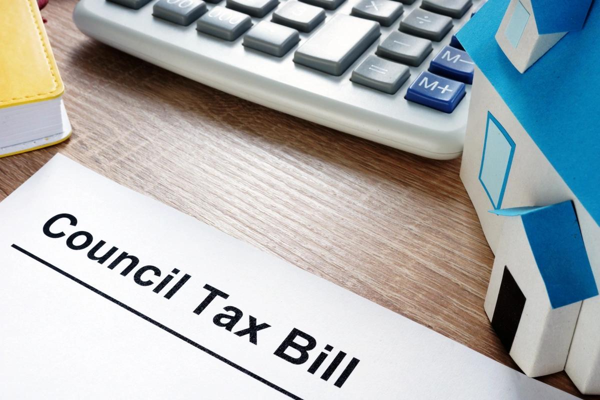 Close-up of a council tax bill on a table next to a calculator and a model house