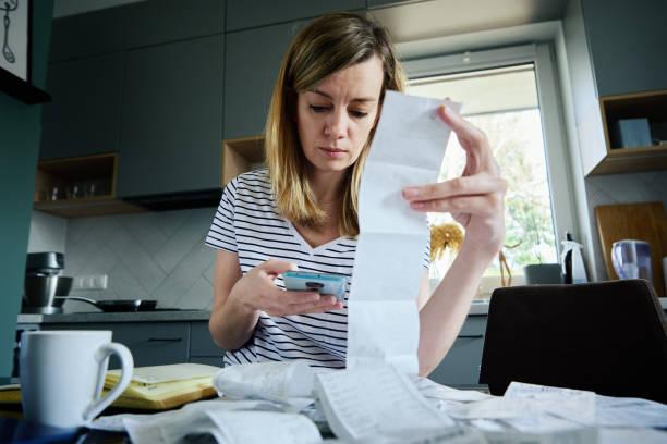 Image of a woman looking over receipts and bills. Five million people living in negative budgets