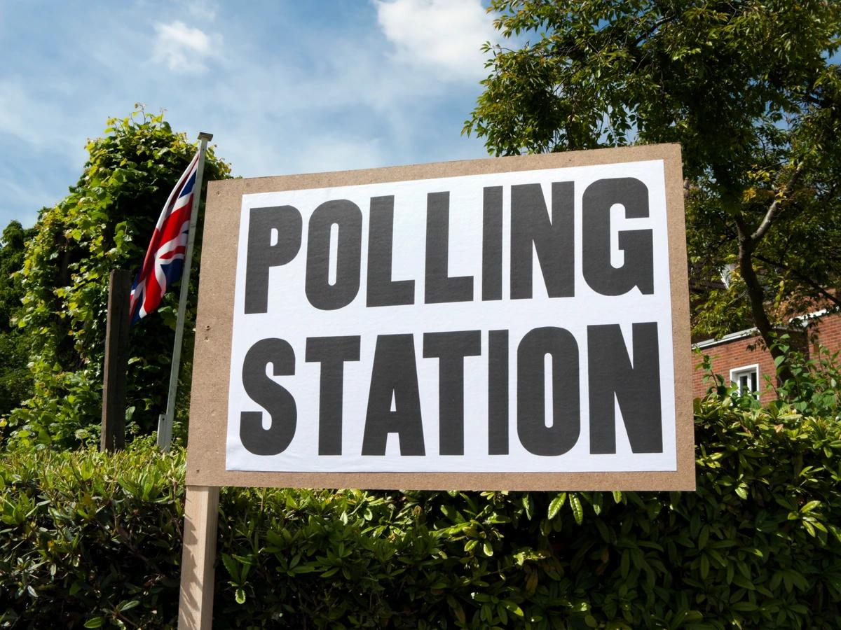 Polling station sign with a union jack flying in the background
